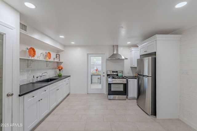 kitchen featuring sink, white cabinetry, ornamental molding, appliances with stainless steel finishes, and wall chimney range hood