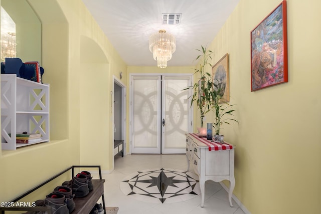 entrance foyer featuring french doors, light tile patterned floors, and an inviting chandelier