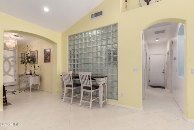 dining room with a notable chandelier, light tile patterned floors, and vaulted ceiling