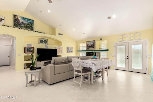 tiled living room featuring ceiling fan, vaulted ceiling, and french doors