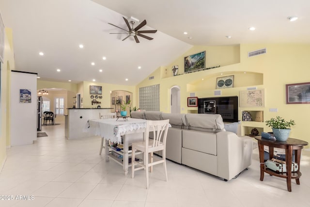 living room featuring ceiling fan with notable chandelier, light tile patterned floors, and high vaulted ceiling