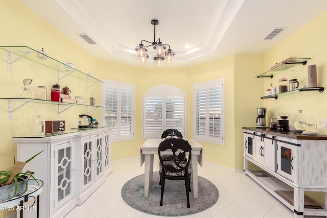 tiled dining room featuring an inviting chandelier, a raised ceiling, and plenty of natural light