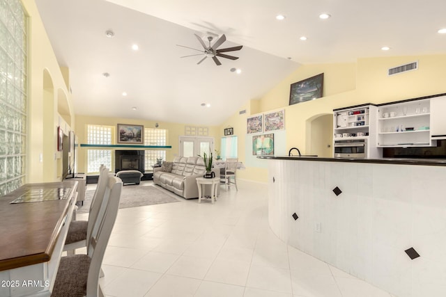 living room with ceiling fan, light tile patterned floors, high vaulted ceiling, and a tiled fireplace