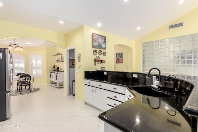 kitchen featuring stainless steel refrigerator, white cabinetry, sink, a notable chandelier, and light tile patterned floors