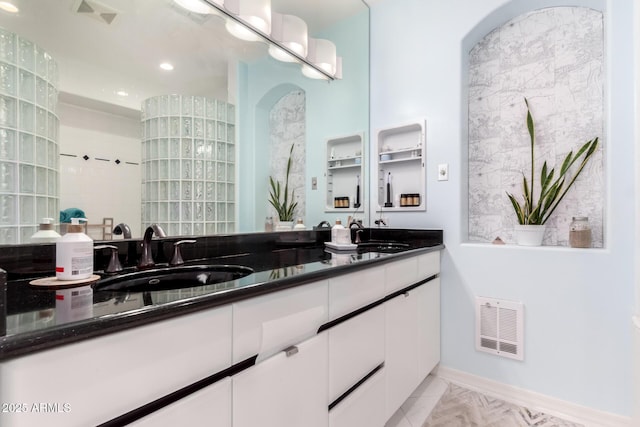 bathroom featuring a tile shower, tile patterned flooring, and vanity