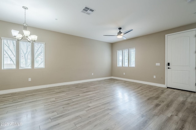 empty room with light wood finished floors, visible vents, baseboards, and ceiling fan with notable chandelier