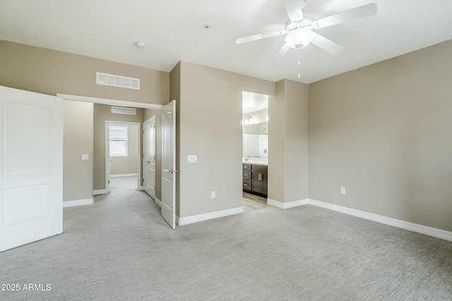 unfurnished bedroom with light colored carpet, ensuite bathroom, baseboards, and visible vents