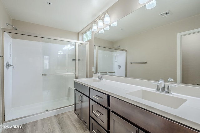 bathroom with wood finished floors, a stall shower, and a sink