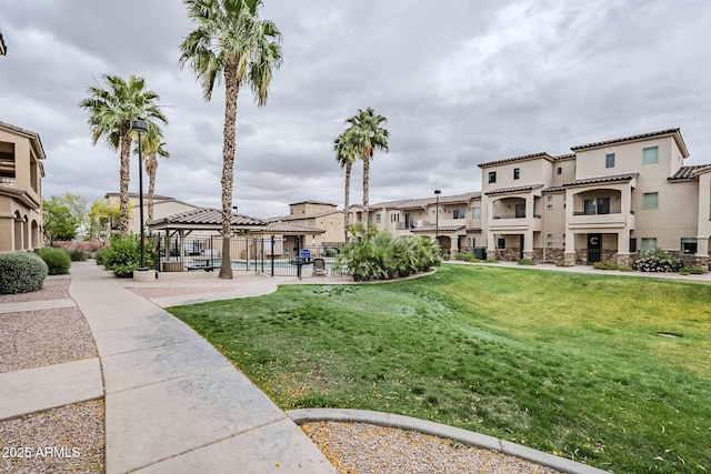 view of community featuring a yard, a gazebo, a residential view, and fence