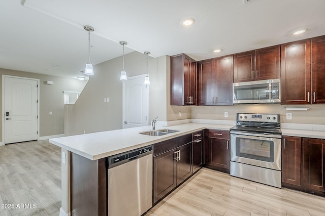 kitchen with light wood-type flooring, light countertops, appliances with stainless steel finishes, and a sink