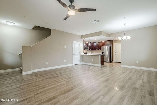unfurnished living room featuring light wood-type flooring, baseboards, visible vents, and ceiling fan with notable chandelier
