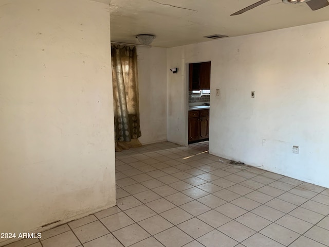 empty room with ceiling fan and light tile patterned floors