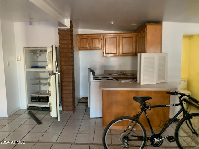 kitchen with stove, lofted ceiling, and light tile patterned floors