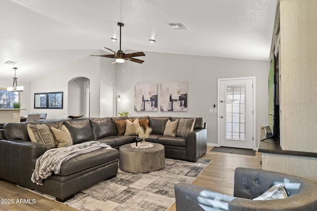 4111 S Dewdrop Ct, Gilbert, AZ 85297 - living room featuring lofted ceiling, arched walkways, wood finished floors, a ceiling fan, and a chandelier