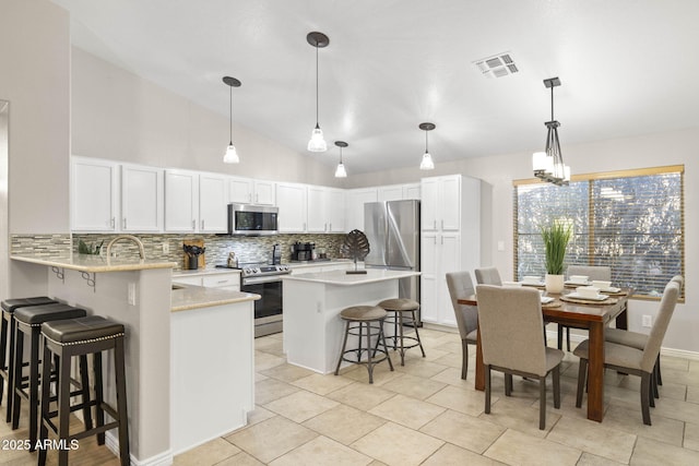 4111 S Dewdrop Ct, Gilbert, AZ 85297 - kitchen featuring stainless steel appliances, decorative backsplash, a kitchen bar, light countertops, and vaulted ceiling