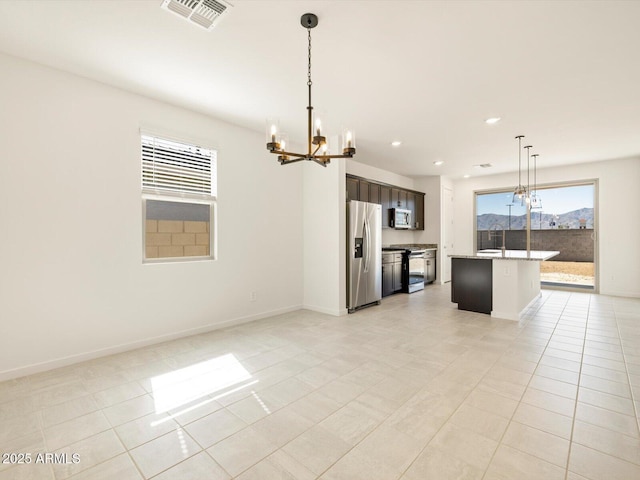 kitchen with visible vents, a kitchen island, stainless steel appliances, pendant lighting, and a notable chandelier