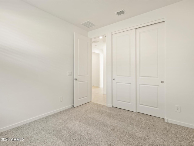 unfurnished bedroom with light colored carpet, a closet, visible vents, and baseboards