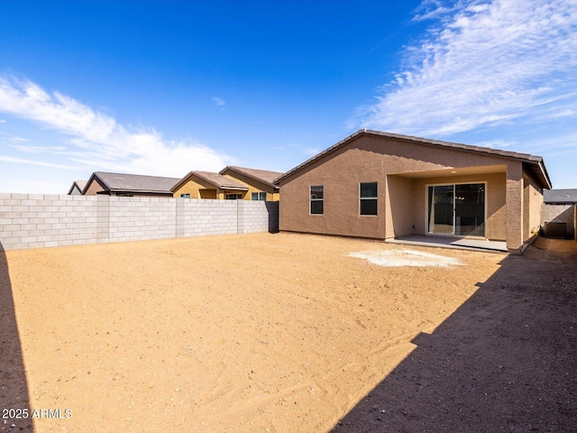 rear view of house with a fenced backyard and stucco siding