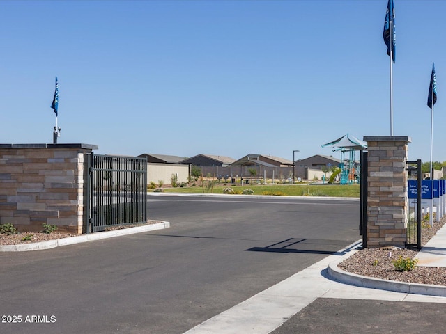 view of road featuring street lights, a gate, and curbs