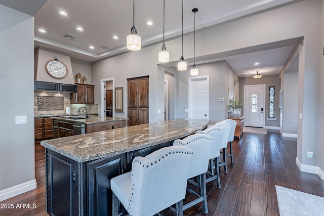 kitchen with visible vents, dark stone counters, a spacious island, dark wood-style floors, and decorative light fixtures