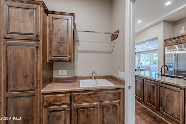 kitchen featuring dark wood-style flooring, light countertops, a sink, and built in refrigerator