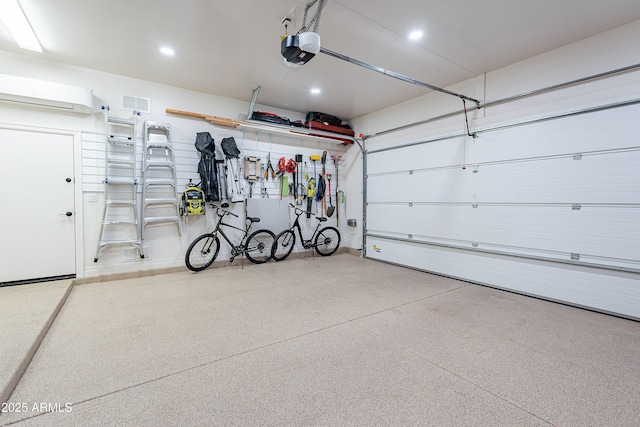 garage with a wall mounted AC, recessed lighting, visible vents, and a garage door opener