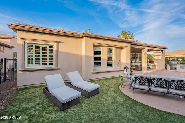 rear view of house with a lawn, a patio, fence, outdoor lounge area, and stucco siding