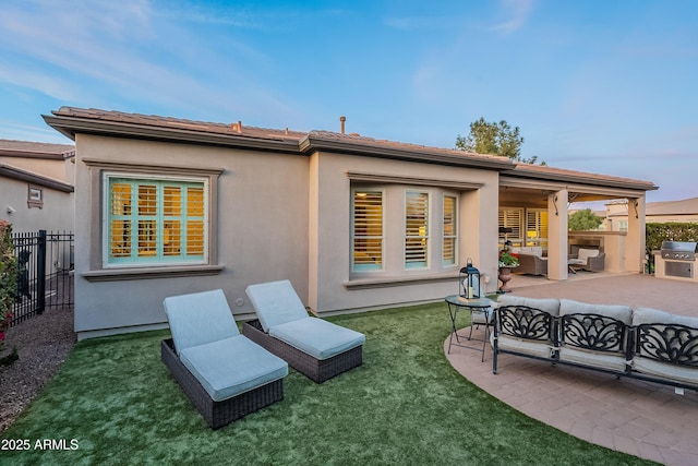 rear view of house with fence, a patio, an outdoor living space, and stucco siding