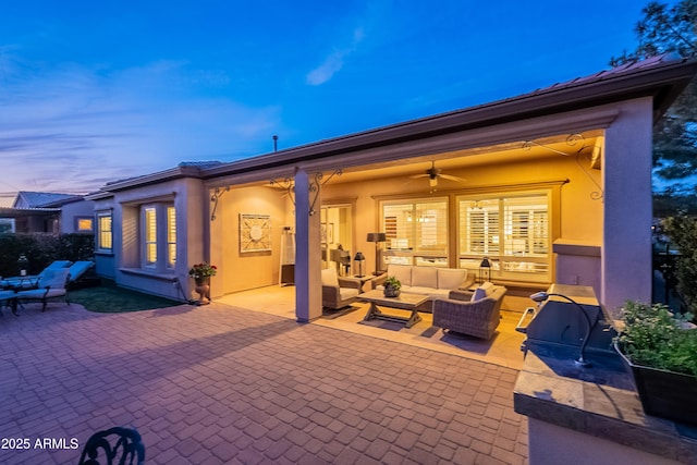 patio terrace at dusk featuring ceiling fan and an outdoor living space