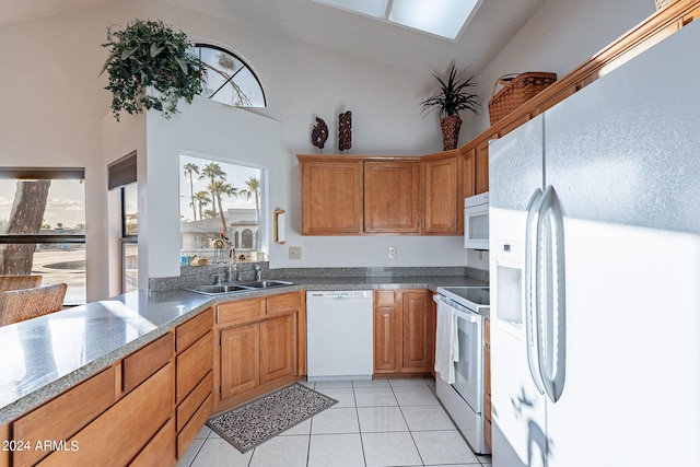 kitchen with high vaulted ceiling, sink, light tile patterned floors, and white appliances