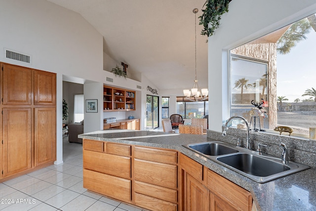 kitchen with sink, decorative light fixtures, an inviting chandelier, light tile patterned floors, and high vaulted ceiling