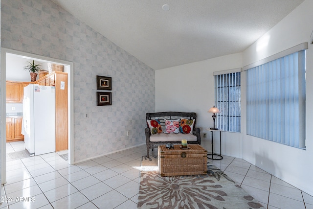 living area with lofted ceiling, a textured ceiling, and light tile patterned floors