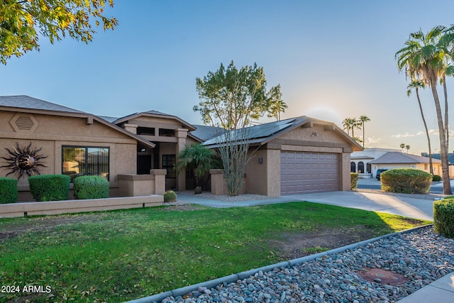 view of front of home with solar panels, a lawn, and a garage