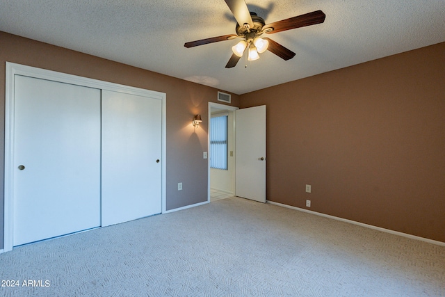 unfurnished bedroom with a closet, ceiling fan, a textured ceiling, and light colored carpet