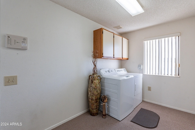 laundry room featuring cabinets, a textured ceiling, light carpet, and washing machine and clothes dryer