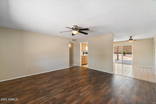 spare room featuring a textured ceiling, ceiling fan, and dark wood-type flooring