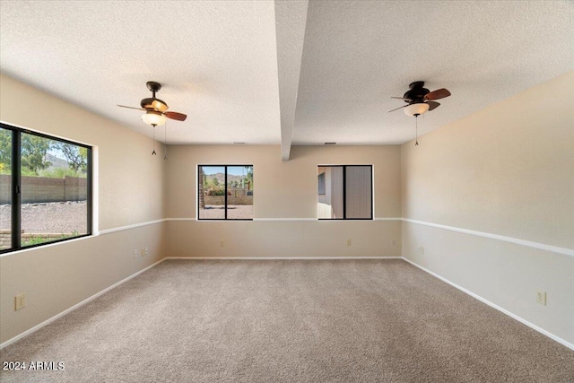 carpeted empty room with ceiling fan, beam ceiling, and a textured ceiling