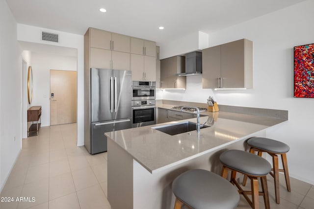 kitchen with wall chimney exhaust hood, a breakfast bar, kitchen peninsula, and stainless steel appliances