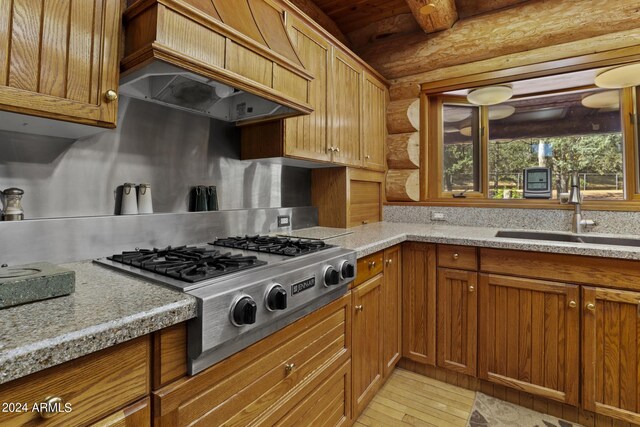 703 N Chaparral Pines Dr, Payson, AZ 85541 - kitchen featuring stainless steel gas cooktop, a sink, brown cabinets, log walls, and custom exhaust hood