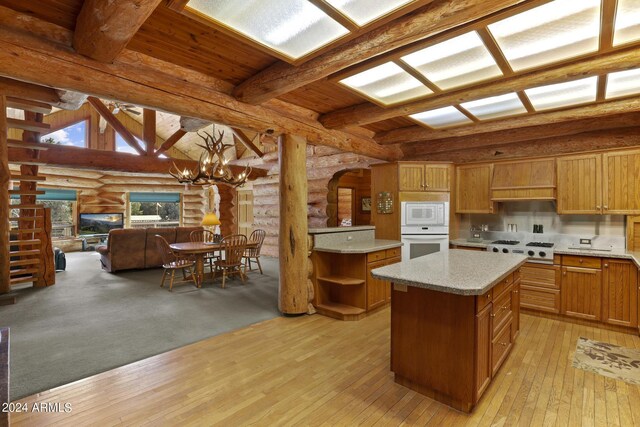 kitchen with an inviting chandelier, light wood-type flooring, rustic walls, and a kitchen island