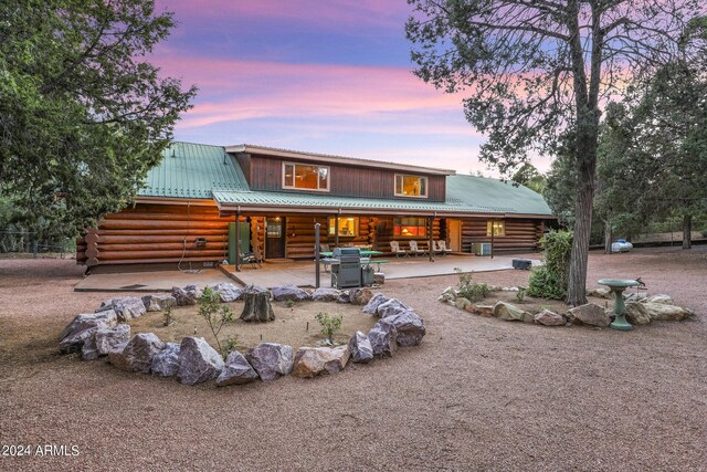703 N Chaparral Pines Dr, Payson, AZ 85541 - back of house at dusk featuring log siding, a patio, and metal roof