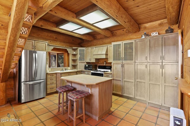 kitchen featuring custom exhaust hood, stainless steel fridge, a kitchen island, white gas stove, and a kitchen bar