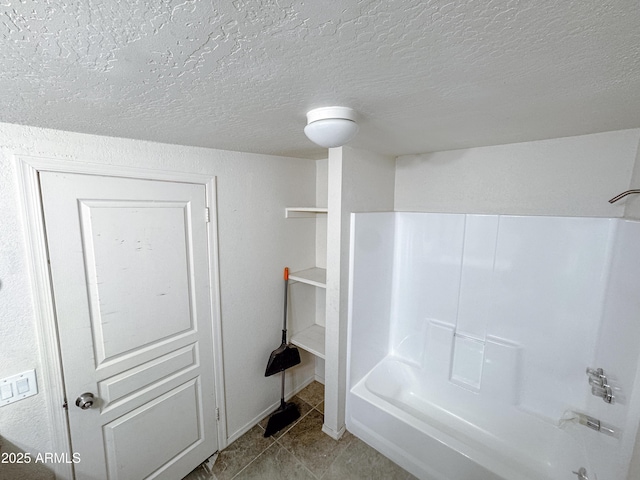 bathroom with washtub / shower combination, tile patterned flooring, and a textured ceiling