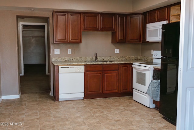 kitchen featuring light stone countertops, sink, and white appliances