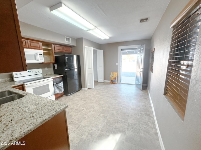 kitchen featuring light stone counters, sink, and white appliances