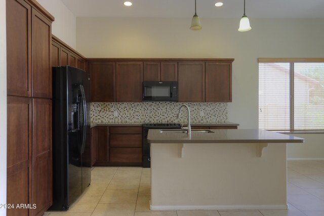 kitchen featuring decorative light fixtures, light tile patterned flooring, black appliances, and tasteful backsplash