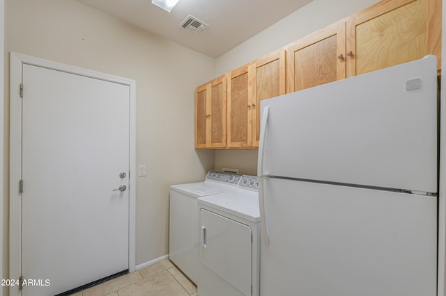 laundry room with light tile patterned floors, washer and dryer, and cabinets