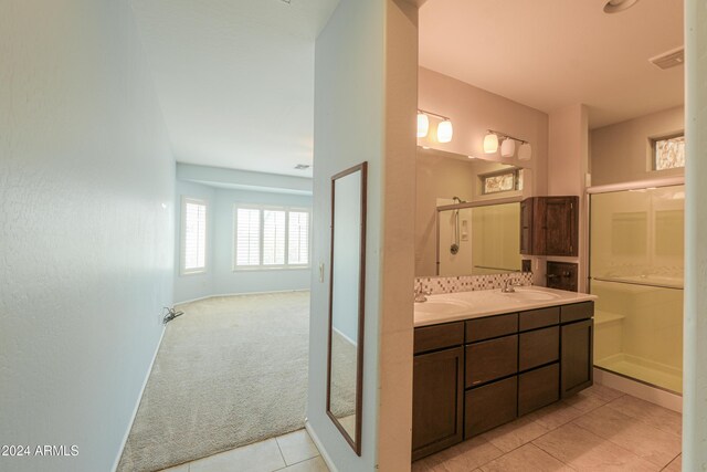 bathroom with tile patterned floors, double vanity, and a shower with door