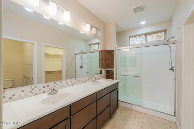 bathroom with toilet, tasteful backsplash, tile patterned floors, walk in shower, and dual bowl vanity