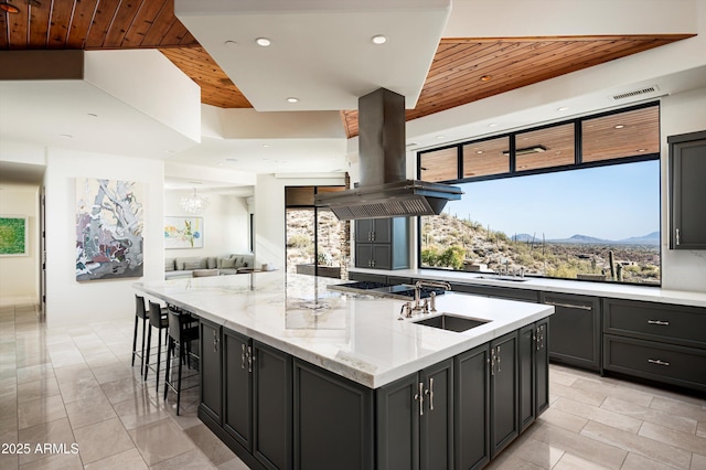 kitchen featuring wooden ceiling, island range hood, stainless steel gas cooktop, a spacious island, and visible vents